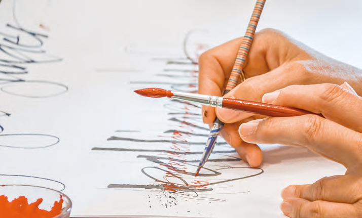 Hände mit Kalligrafiestift und Pinsel in der Hand. 